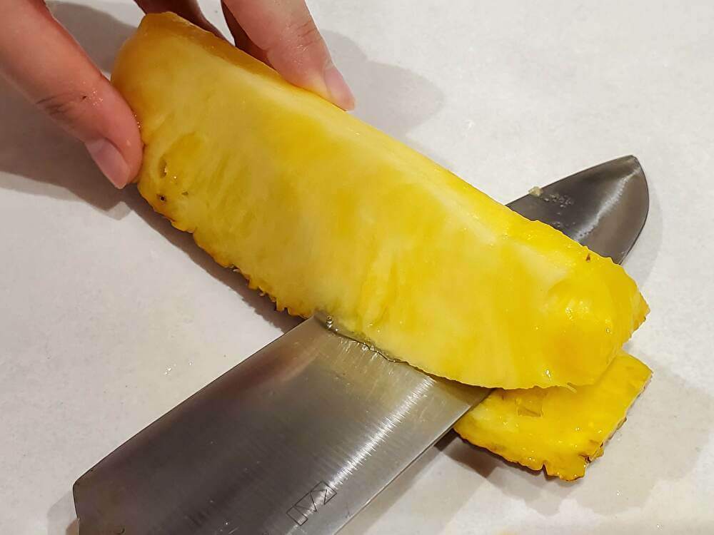 パイナップルの皮を切り落とす